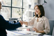 © Parichat - Businesswoman Shaking Hands with Colleague in Modern Office Setting, Smiling and Engaging in Professional Meeting