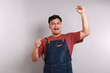 © ArvStd - Happy asian barista celebrating victory, raising hands up and shouting for joy, wearing blue apron, shop uniform, standing against white background.