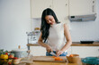 © Parichat - Young Woman Preparing Fresh Vegetables in a Modern Kitchen with a Bright and Cheerful Atmosphere