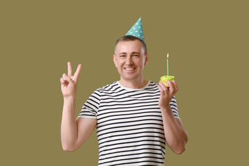 Sticker - Mature man with birthday tartlet showing victory gesture on green background