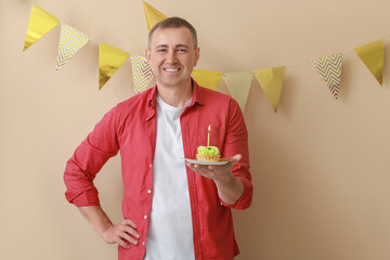 Poster - Mature man with birthday tartlet on beige background