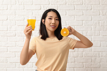 Sticker - Beautiful Asian woman with orange and glass of juice on white brick background