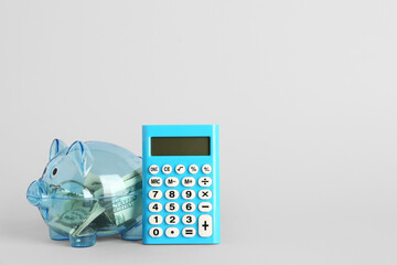 Wall Mural - Calculator, piggy bank and money on light background. Finance concept