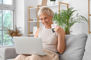 Poster - Mature woman with credit cards and laptop shopping online at home