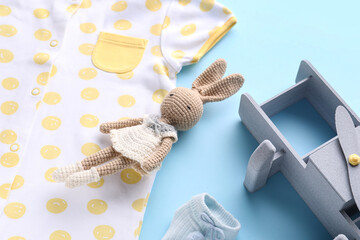 Wall Mural - Baby clothes, toy bunny and plane on color background, closeup