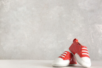 Canvas Print - Stylish baby shoes on white table near grunge grey wall