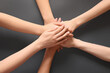 © Pixel-Shot - Group of people putting hands together on grey background. Inclusion concept