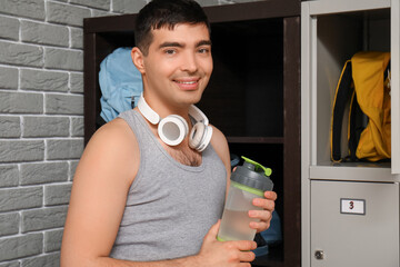 Poster - Sporty young man with water bottle near locker in changing room