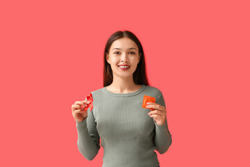 Canvas Print - Pretty young woman with red ribbon and condom on color background. World AIDS Day concept