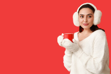 Sticker - Beautiful young woman in warm mittens with cup of hot mulled wine on red background