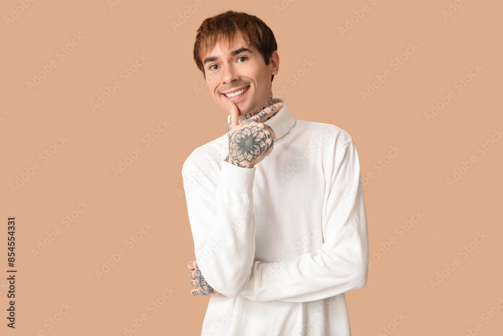 Happy handsome young tattooed man on beige background