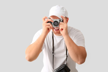 Sticker - Handsome young happy male tourist with camera taking photo on grey background