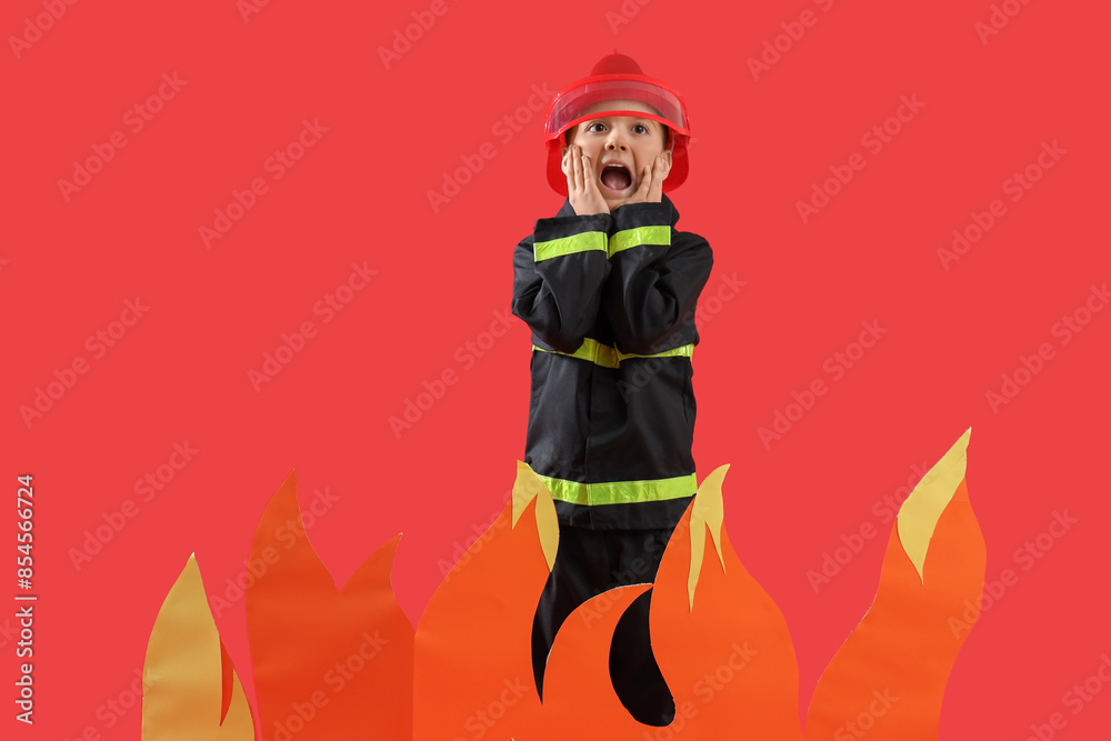 Cute little firefighter with paper flame screaming on red background