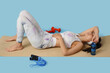 © Pixel-Shot - Sporty young woman tired after training with dumbbells and skipping rope on blue background