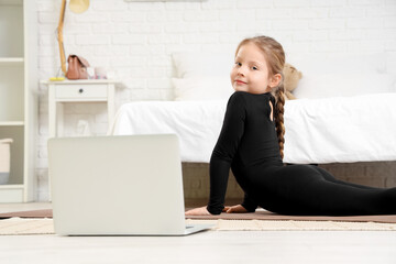 Poster - Cute little girl with mat and laptop doing gymnastics in bedroom