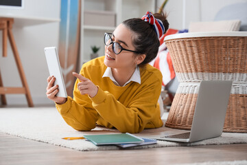 Wall Mural - Female student studying with tablet computer on floor at home