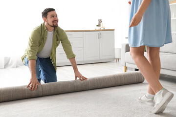 Wall Mural - Young couple rolling out carpet at home