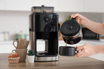 Wall Mural - Woman with modern coffee machine pouring espresso from pot into cup in kitchen