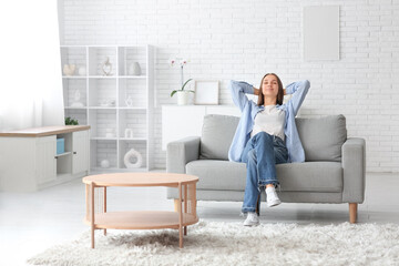 Wall Mural - Young pretty woman sitting on couch at home