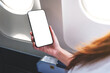© Farknot Architect - Mockup image of a hand holding mobile phone with blank desktop screen next to an airplane window