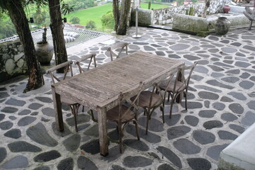 Wooden tables and chairs in the courtyard of a cafe with an open concept