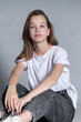 © yavdat - A young girl in casual attire looks thoughtfully into the camera, seated against a neutral background. Youth introspection reflects the complexities of adolescence in modern society.