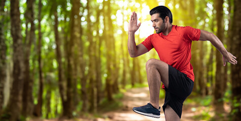 Wall Mural - Athletic and sporty man running posture at outdoor green forest exercise session for fit physique and healthy outdoor sport lifestyle. Gaiety green foliage tree exercise workout training.