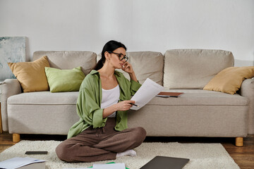 A woman in casual attire sits on the floor, engrossed in reading a paper.