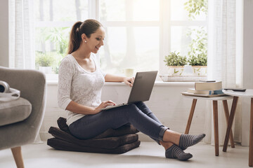 Wall Mural - Young woman networking with her laptop at home