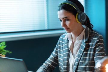 Wall Mural - Young woman wearing headphones and working