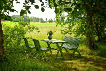 Green wooden table, bench and chairs. A place to relax in nature.