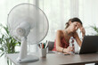 © StockPhotoPro - Woman cooling herself with an electric fan