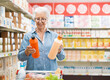© StockPhotoPro - Senior customer comparing products at the supermarket