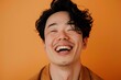 © CogniLens - Portrait of a glad asian man in his 30s laughing over soft orange background