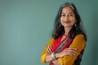 © CogniLens - Portrait of a merry indian woman in her 30s with arms crossed in soft teal background