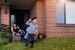 © Austockphoto - Five year old boy running around on front yard of home with family sitting on steps