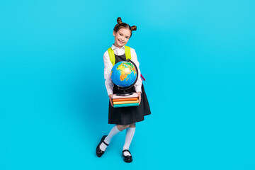 Sticker - Full body photo of cute little girl backpack hold books globe dressed stylish school uniform isolated on blue color background