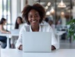 © Nuchylee - Smiling businesswoman working on laptop in modern office, bright and professional workspace, productivity and success.