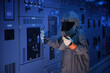 © pinyo - Engineer wears a arc flash protection suit for inspection electrical current and checking status switch gear electrical energy distribution substation, safety suit.
