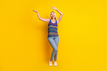 Wall Mural - Photo portrait of young energetic blonde lady in jeans and singlet dancing at dancehall nightclub isolated on yellow color background