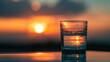 © Wavezaa - a glass half full of water sits on a table outside as the sun sets in the background