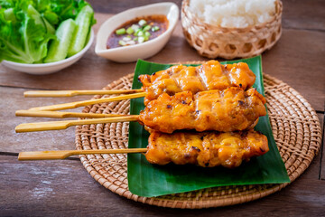 Wall Mural - Grilled chicken skewers on banana leaf served with sticky rice and vegetable