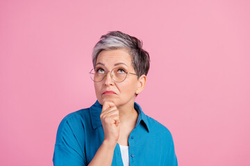 Wall Mural - Photo portrait of lovely pensioner lady look unsure minded up empty space dressed stylish blue garment isolated on pink color background