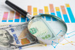 © Pakawadee - Magnifying glass with US dollar banknotes on graph. Finance business and trading.