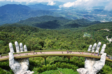 statue of hands holding a bridge over a forest, towering over landscape vietnam da nang ba na hills 