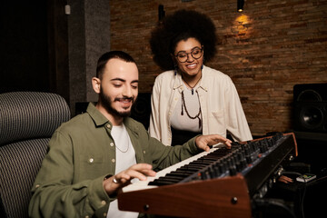 A man and a woman, musicians, collaborating on a music band rehearsal in a professional recording studio.