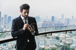 © Jack Tamrong - Smart and handsome businessman standing at balcony with cityscape background