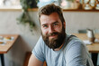 © frankb - Bearded man sitting in a cozy cafe, smiling at the camera