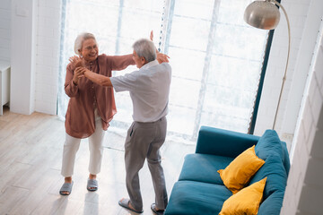 Wall Mural - Celebrating Retirement: Elderly Couple Embrace Love and Happiness at Home, Fun-filled Life of Dancing, Smiling, and Bonding Together, Cherishing Family and Romance in Their Golden Years