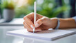 © Your Hand Please - woman's hand writing on an empty white paper on a white table, with a blurred background. The image captures the intimate act of writing, emphasizing personal expression and creativity